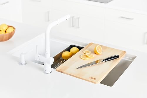 Black granite single bowl undermount sink installed in white countertop with cutting board and white faucet visible.