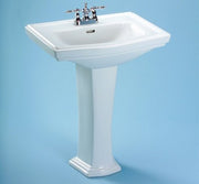 White rectangular pedestal sink with faucet holes and chrome faucet fixture on blue background.