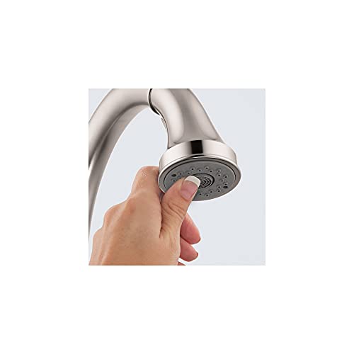 Chrome kitchen faucet with high arc spout and pull-down spray head held in hand.