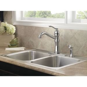 Chrome kitchen faucet with high arc spout, single handle, and side spray mounted on double sink.