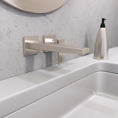 Brushed nickel wall-mount faucet with single lever handle and rectangular spout installed above white sink basin.