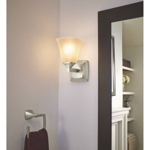 Brushed nickel wall sconce with frosted glass shade mounted above a matching towel ring holder.