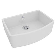 White fireclay farmhouse sink with curved apron front, single bowl, and chrome drain fixture.
