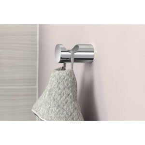 Brushed nickel single robe hook mounted on wall with white towel hanging from it.