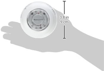 Round white mechanical thermostat with temperature dial, shown in hand for scale at 3.8 inches.