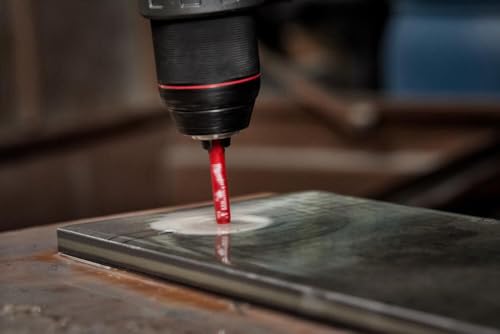 Diamond grit hole saw bit with red coating drilling into gray tile surface.