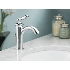Brushed nickel single-handle bathroom faucet with curved low-arc spout mounted on white sink counter.