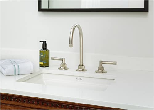 Antique gold widespread lavatory faucet with curved C-spout and lever handles installed on white sink counter.