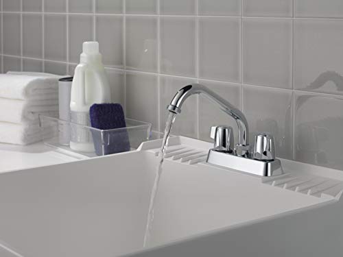 Chrome two-handle laundry faucet with curved spout mounted on white sink basin.