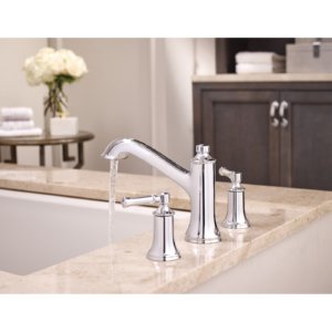 Chrome two-handle high arc faucet with spout and side sprayer on marble tub deck.