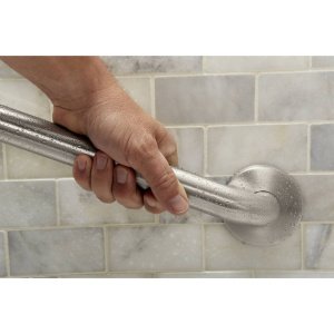 Hand gripping 18-inch stainless steel grab bar mounted on tile wall in bathroom.