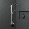 Chrome handheld showerhead with vertical slide bar mount and control valve on dark tile wall.