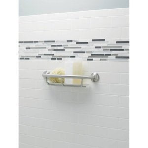 Brushed nickel grab bar with integrated shelf mounted on white tile bathroom wall.