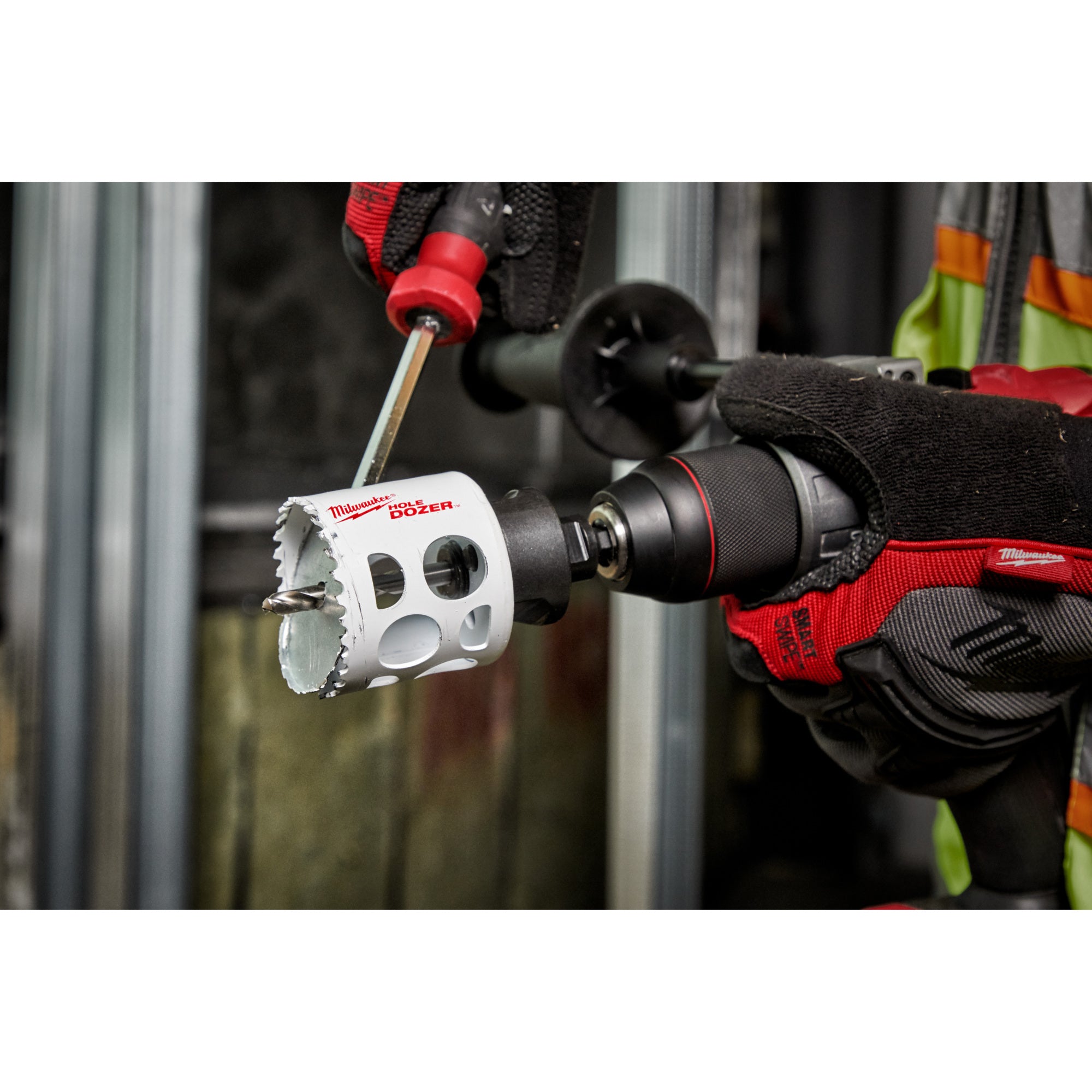 Milwaukee 2-inch bi-metal hole saw with white body and saw teeth, attached to power drill with red and black grip.