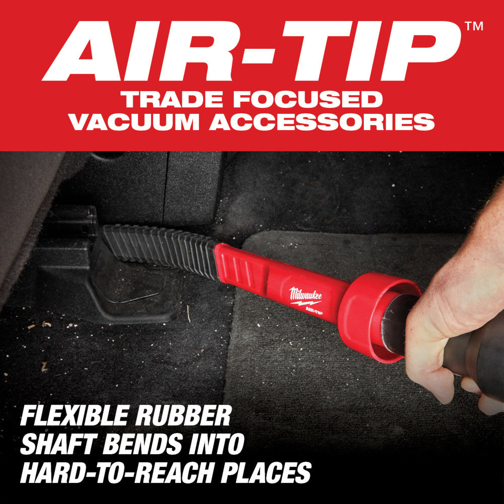 Red and black flexible crevice tool with ribbed rubber shaft being used to clean tight spaces in a vehicle interior.