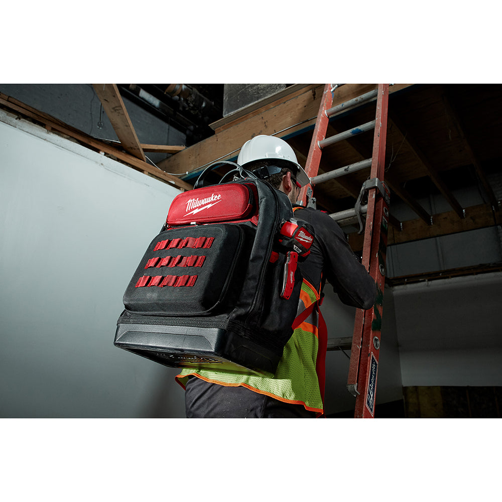 Black and red Milwaukee backpack with red pocket organizers worn by worker on jobsite ladder.