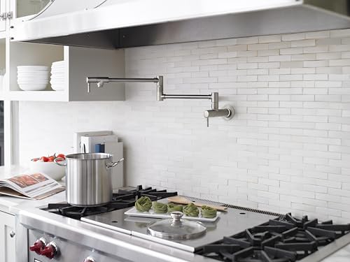 Chrome wall-mounted pot filler faucet with articulating arm extended over kitchen stovetop.