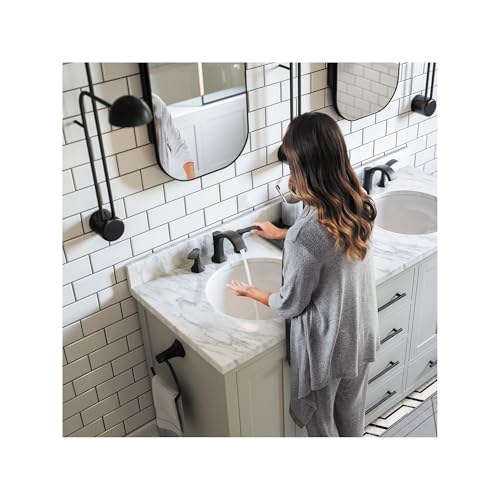 Matte black widespread faucet with two handles installed on white marble bathroom sink.