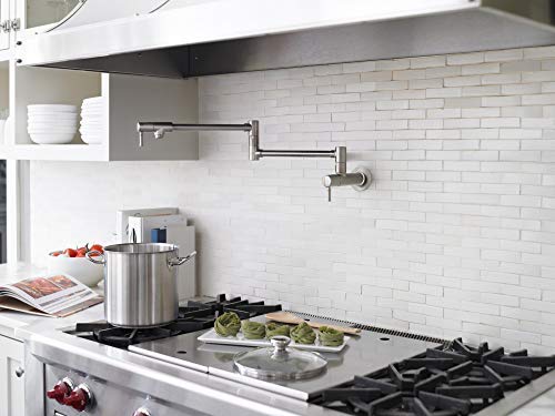 Polished nickel wall-mounted pot filler faucet with articulating arm installed above a kitchen stovetop.