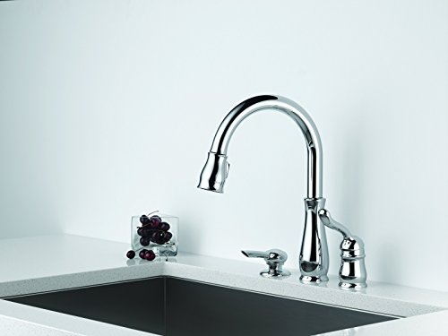 Chrome pull-down kitchen faucet with single lever handle and integrated soap dispenser mounted on countertop above sink.