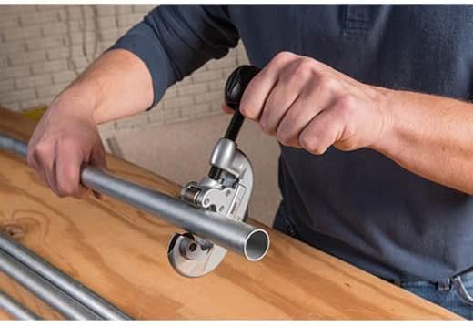 Person using RIDGID tubing cutter on metal pipe, demonstrating quick-acting cutting mechanism.