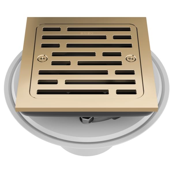 Square shower drain with polished gold grate and linear slot pattern, installed in white mounting ring.