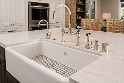 Stainless steel wire grid sink protector fitted inside white farmhouse kitchen sink basin.