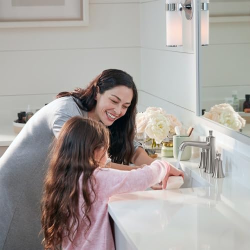 Brushed nickel widespread faucet with pop-up drain installed on white bathroom sink with woman and child using it.