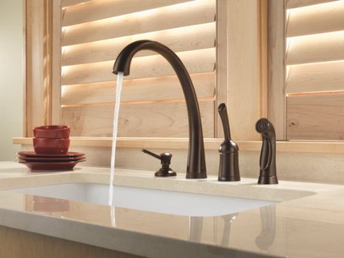 Venetian bronze soap and lotion dispenser with curved spout mounted on white bathroom sink counter.