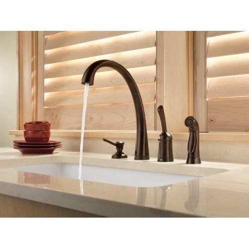 Champagne bronze kitchen faucet with arched spout and matching soap dispenser on white sink counter.