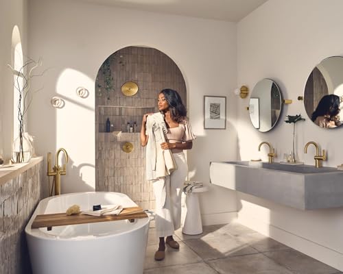 Brushed gold single-handle shower trim kit installed in modern bathroom with white walls and natural lighting.