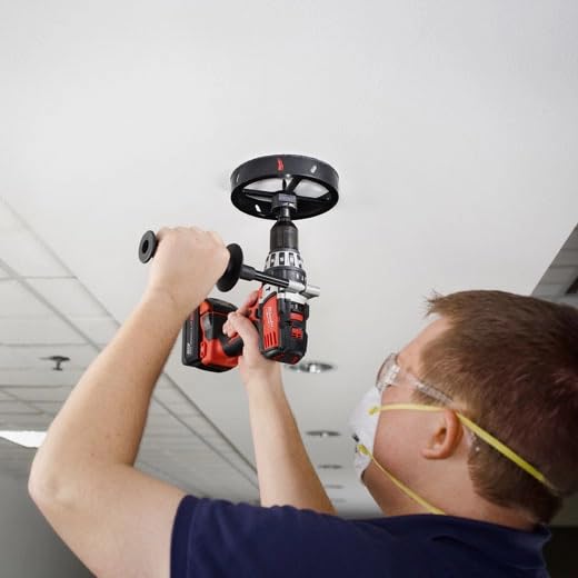 Milwaukee recessed light hole saw with black wheel handle held up to ceiling during installation.