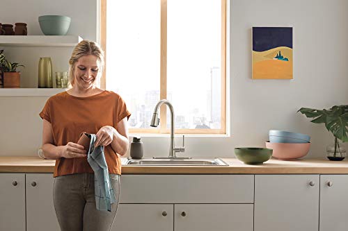 Stainless steel single-handle pull-down kitchen faucet with curved spout installed above sink in kitchen.