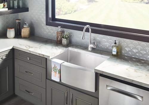 Chrome single-handle kitchen faucet with pull-down sprayer mounted above white apron sink in gray cabinetry.