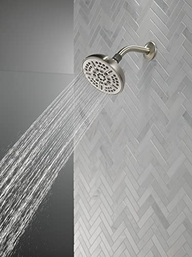 Satin nickel round shower head mounted on wall tile with water streams flowing downward.
