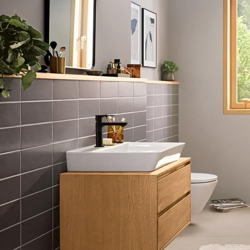Chrome single-hole bathroom faucet with tall curved spout mounted on white vessel sink in wood vanity.