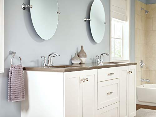 Chrome two-handle bathroom faucet mounted on white vanity with double sink and circular mirrors.