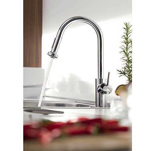Chrome kitchen faucet with high curved spout and pull-down spray head extended over sink.