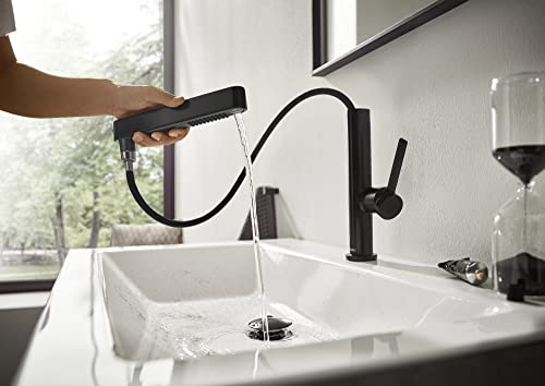 Matte black single-hole kitchen faucet with pull-out spray head extended over white sink.