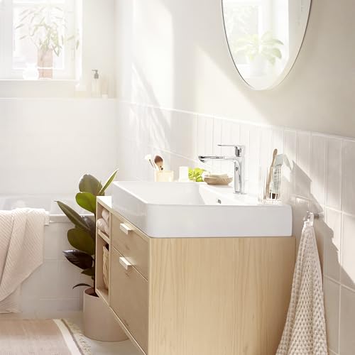 Chrome single-hole bathroom faucet with tall curved spout and pop-up drain installed on white rectangular sink.