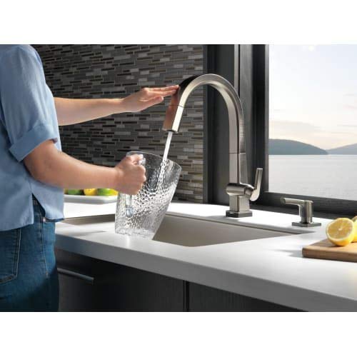 Stainless steel pull-down kitchen faucet with soap dispenser mounted on white countertop sink.