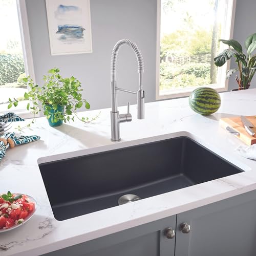 Anthracite single bowl undermount sink with chrome pull-down faucet installed in white countertop.