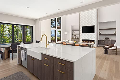 Brushed gold arc kitchen faucet with pull-down spray mounted on white island countertop in modern kitchen.