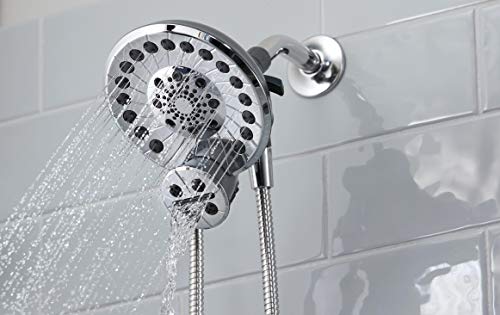 Chrome shower head with multiple spray holes and attached flexible hose, mounted on bathroom tile wall.