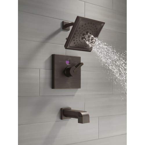 Venetian bronze shower valve trim kit with square showerhead, lever handle, and tub spout mounted on tile wall with water flo