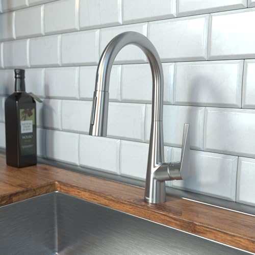 Stainless steel kitchen faucet with high arc spout and pull-down spray head on wood countertop with subway tile backsplash.