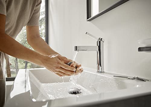 Chrome single-hole bathroom faucet with tall spout and pop-up drain, installed on white sink with running water.