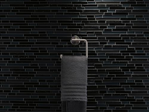 Polished nickel towel ring mounted on black brick wall with dark gray towel hanging from ring.