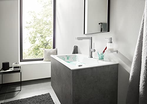 Chrome single-hole bathroom faucet with tall spout and pull-out spray head mounted on dark gray sink.