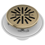 Round shower drain with luxe gold cover and radial slot pattern, mounted on white base ring.